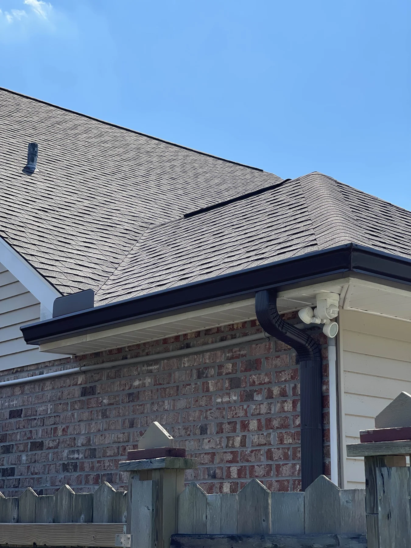 Dark gutter corner and downspout on brick