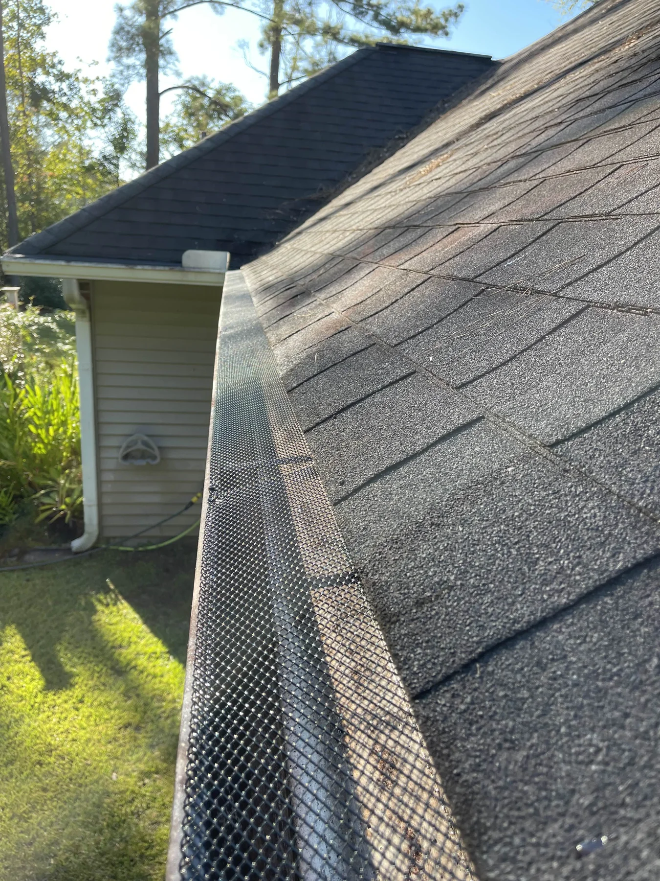 Close-up of mesh gutter protection fitted beside roof shingles