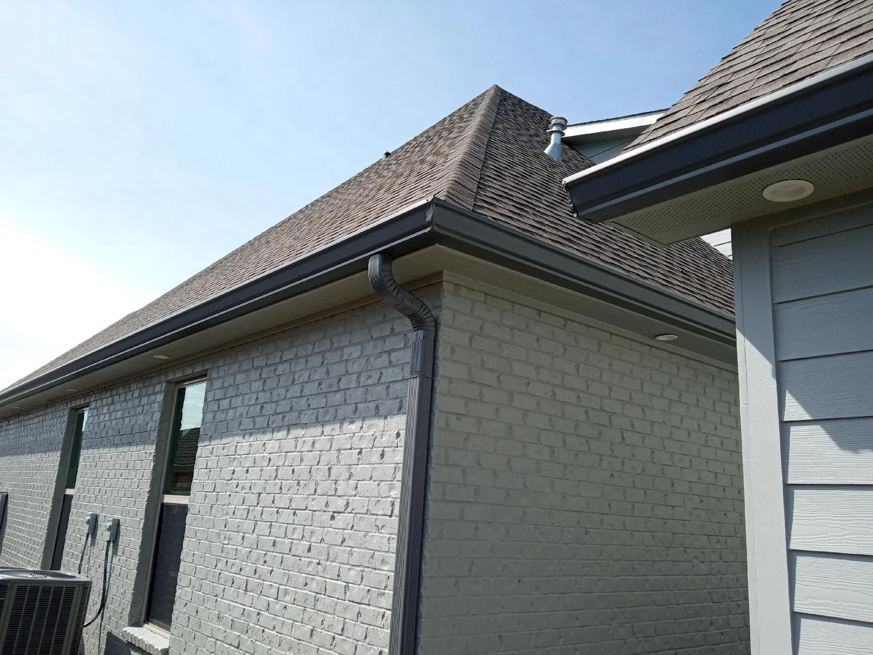 Dark seamless gutters following a brick garage roofline