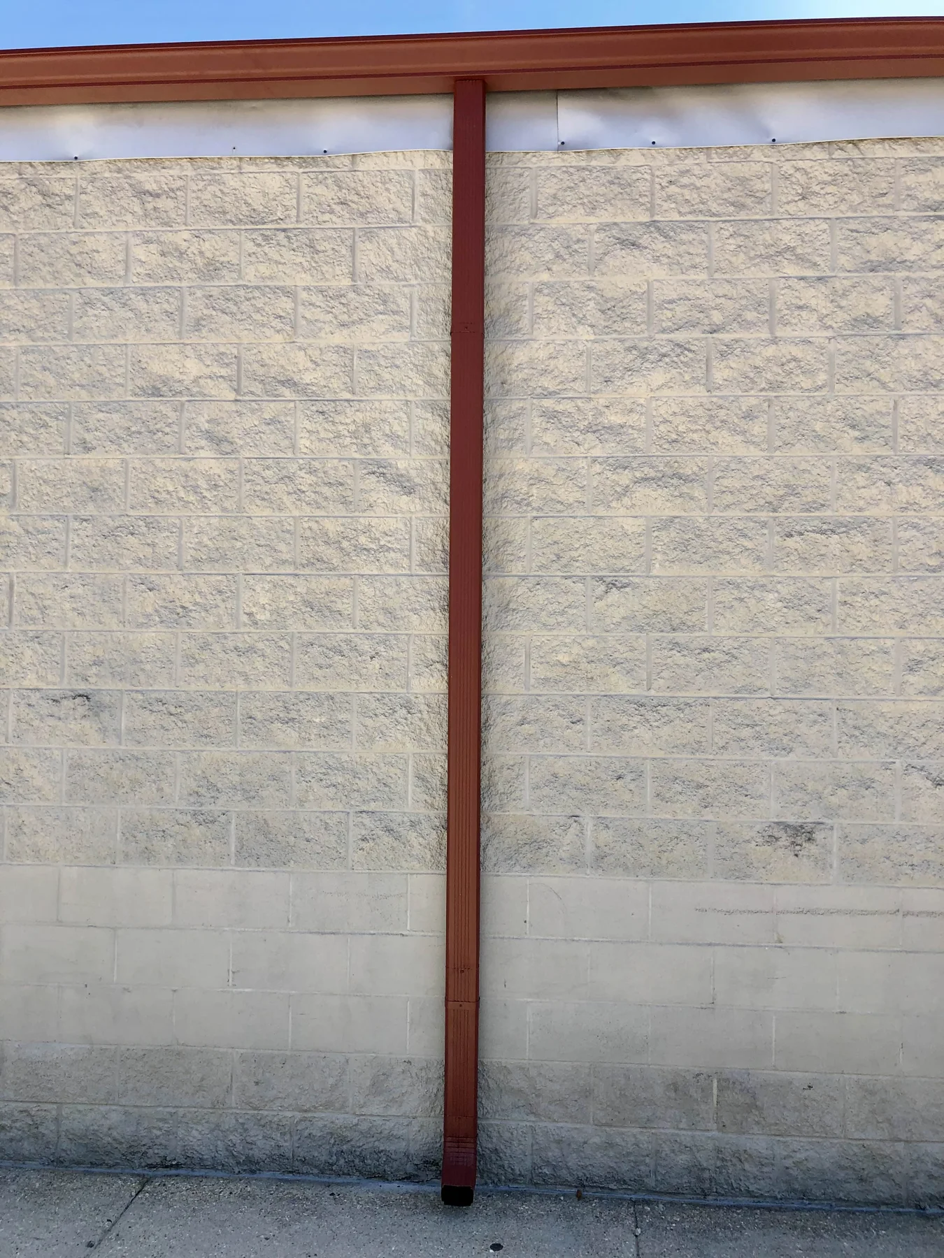 Reddish downspout against a light wall