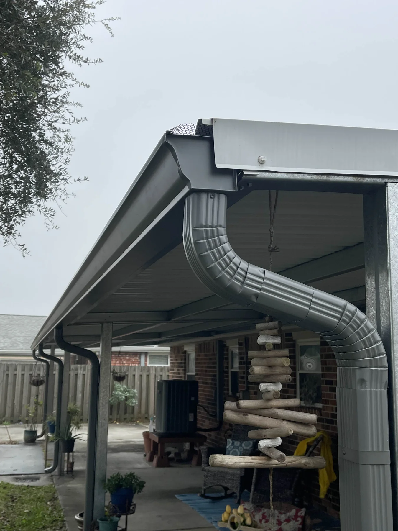 Gutter outlet and downspout connections at a covered patio